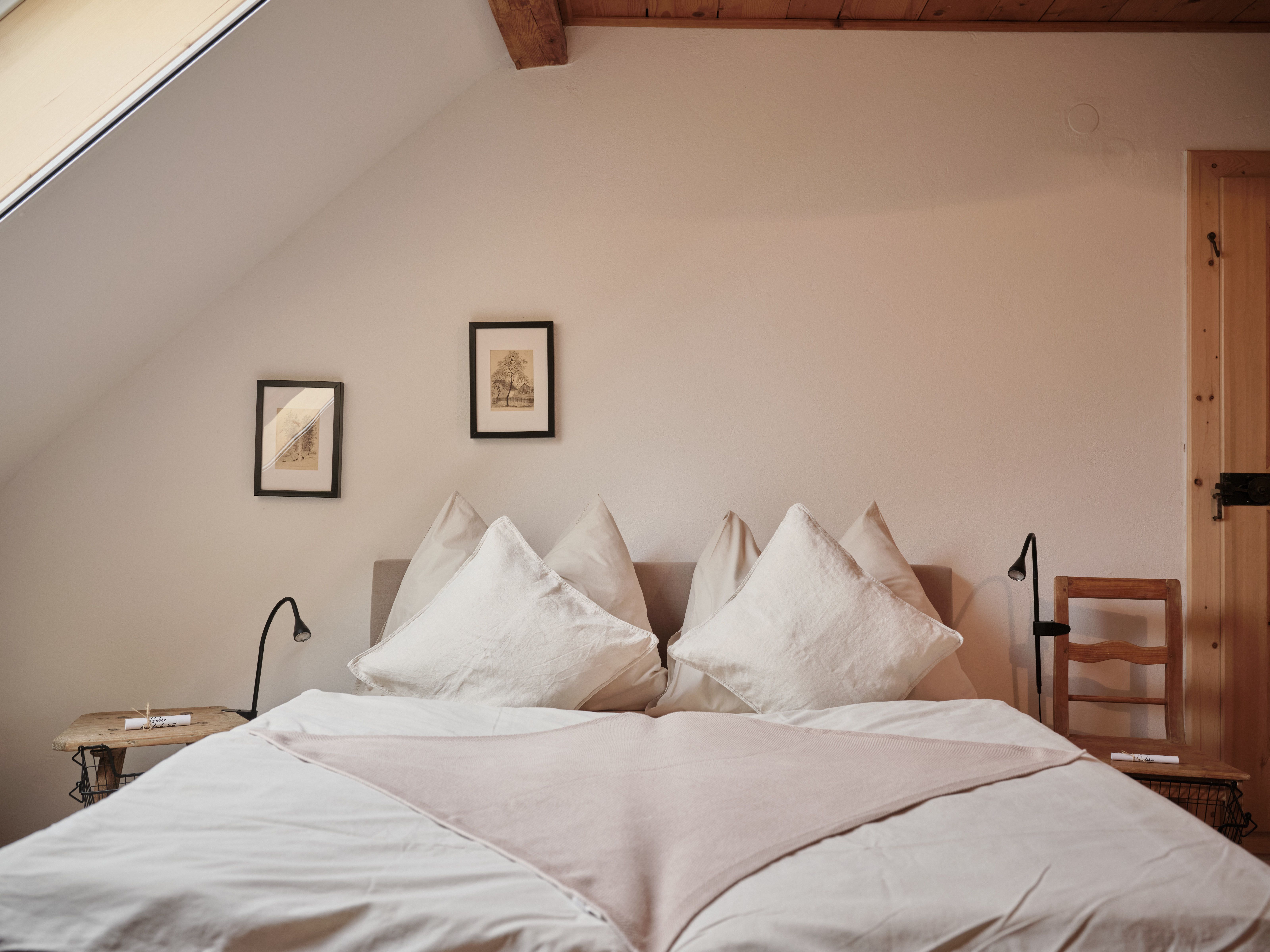 Gemütliches Schlafzimmer mit Dachschräge, Doppelbett, zwei Nachttischen und Wandbildern.