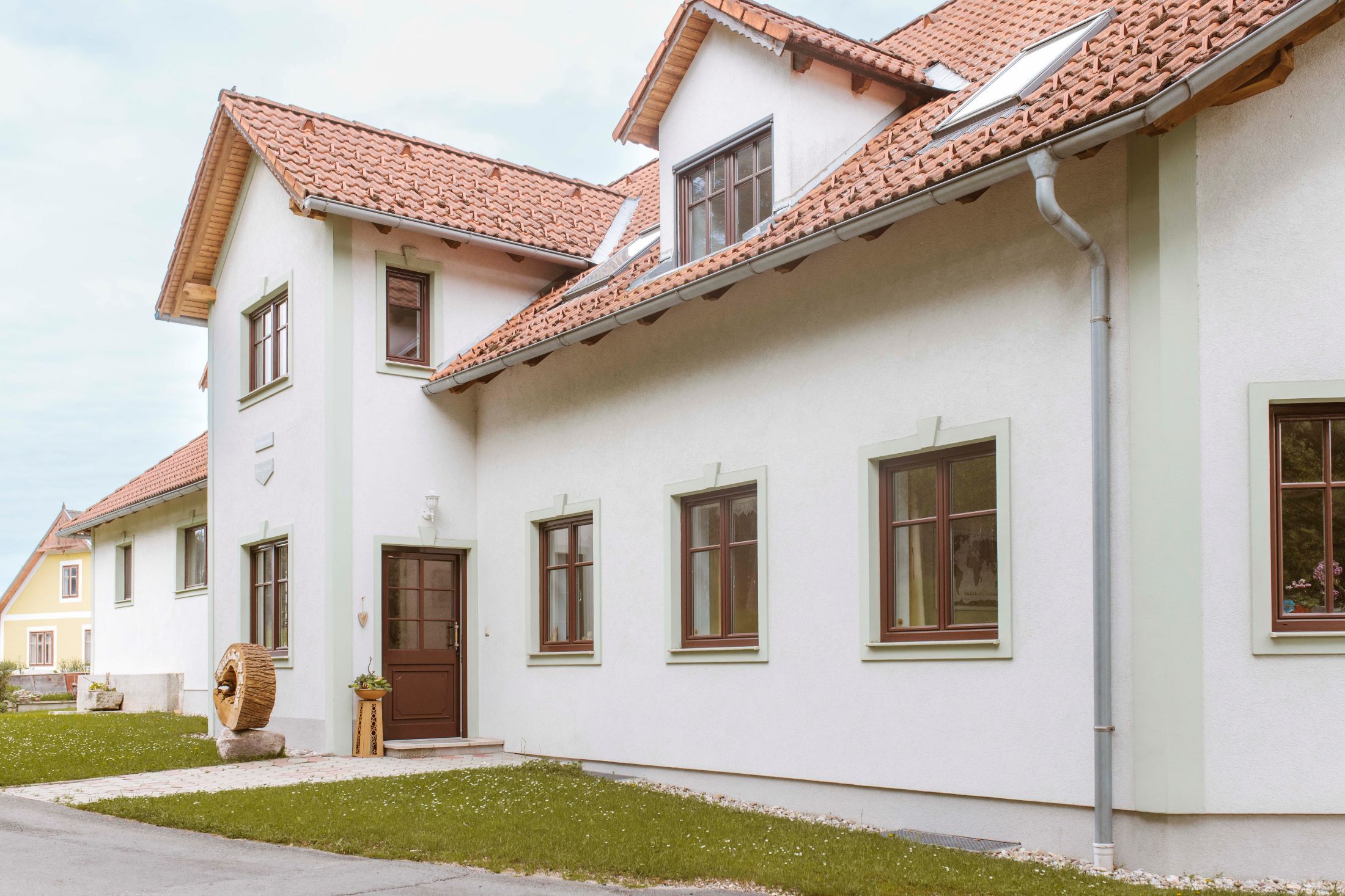 Außenansicht eines Hauses mit roten Ziegeldächern und weißen Wänden.