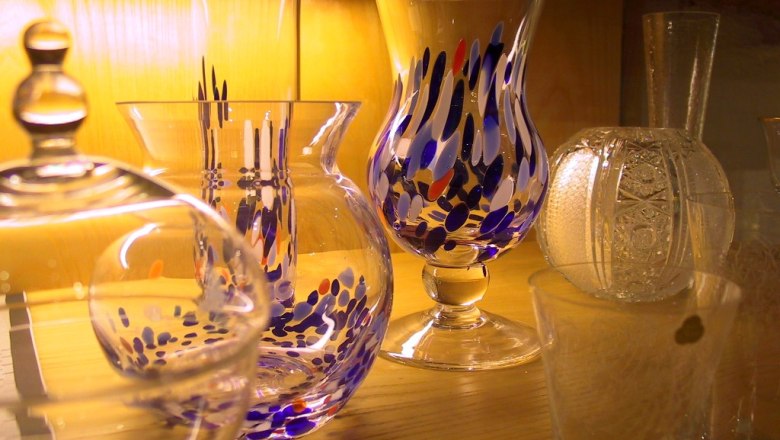 Verschiedene bunte Glasvasen auf einem Holzregal.