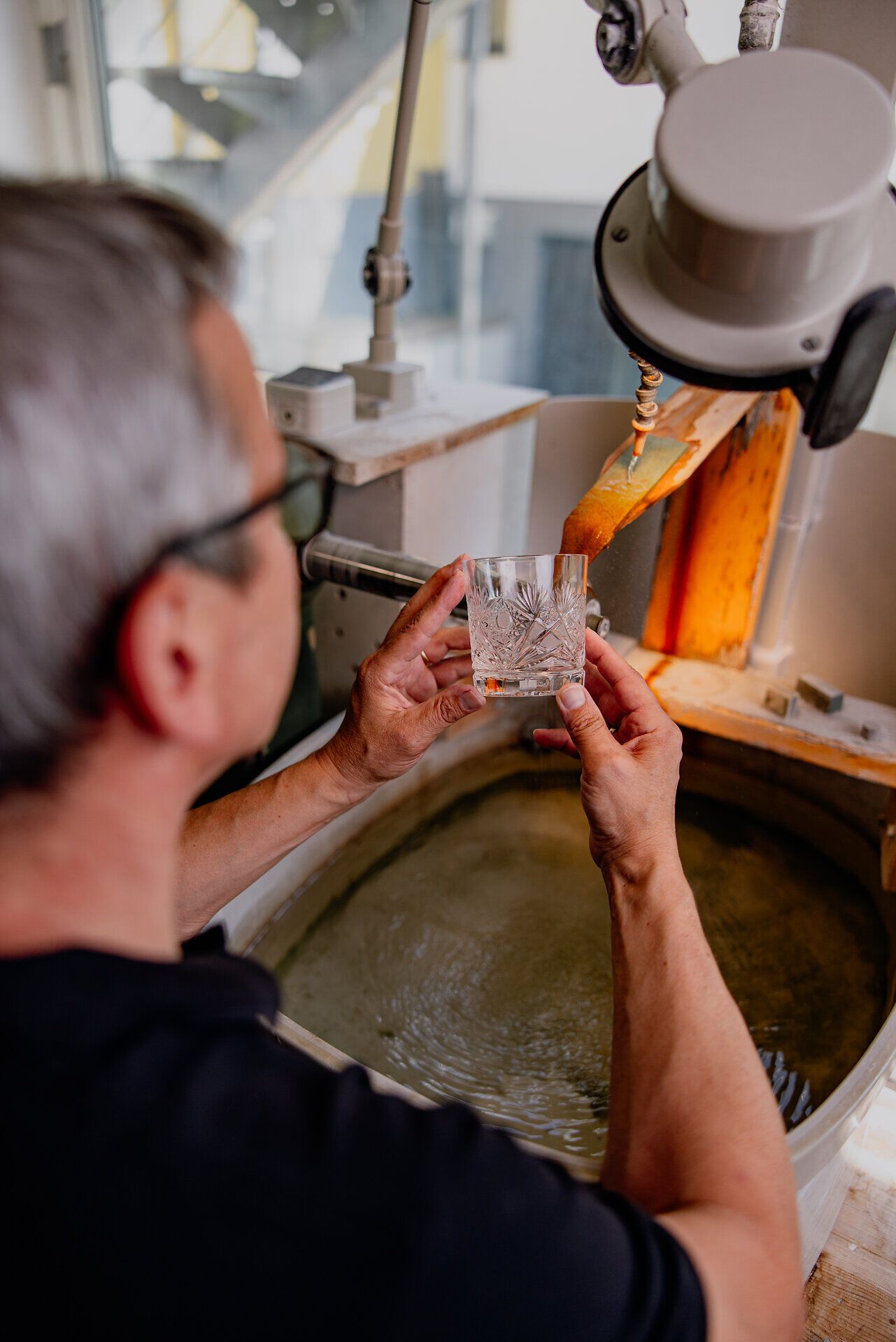 In der faszinierenden Welt des Kristallhandwerks wird mit viel Geschick und Leidenschaft ein funkelndes Glasobjekt geschaffen. Die sanften Lichtreflexe auf der Wasseroberfläche spiegeln die Kreativität und Tradition des Waldviertels wider, während der Handwerker konzentriert sein Meisterwerk betrachtet.