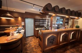 Rustikale Bar mit Holzverkleidung und Bierfässern als Dekoration.