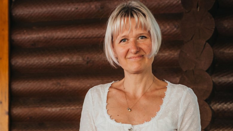 Frau mit blonden Haaren vor Holzwand