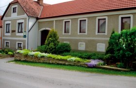 Traditionelles Bauernhaus mit gepflegtem Garten und roten Ziegeld&auml;chern.