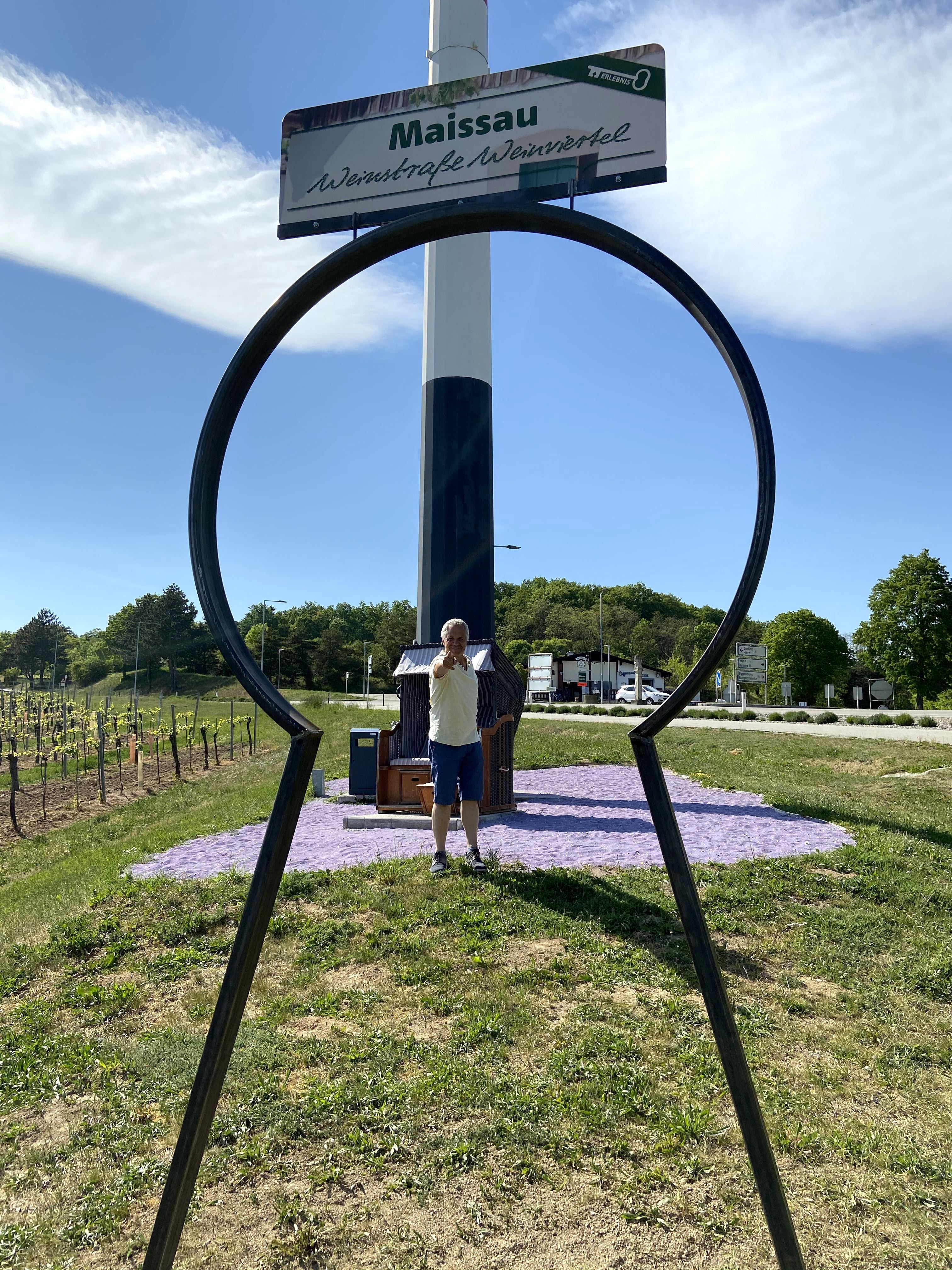 Ein Mann steht hinter einer großen Schlüsselform in Maissau, mit einem Schild der Weinstraße Weinviertel im Hintergrund.