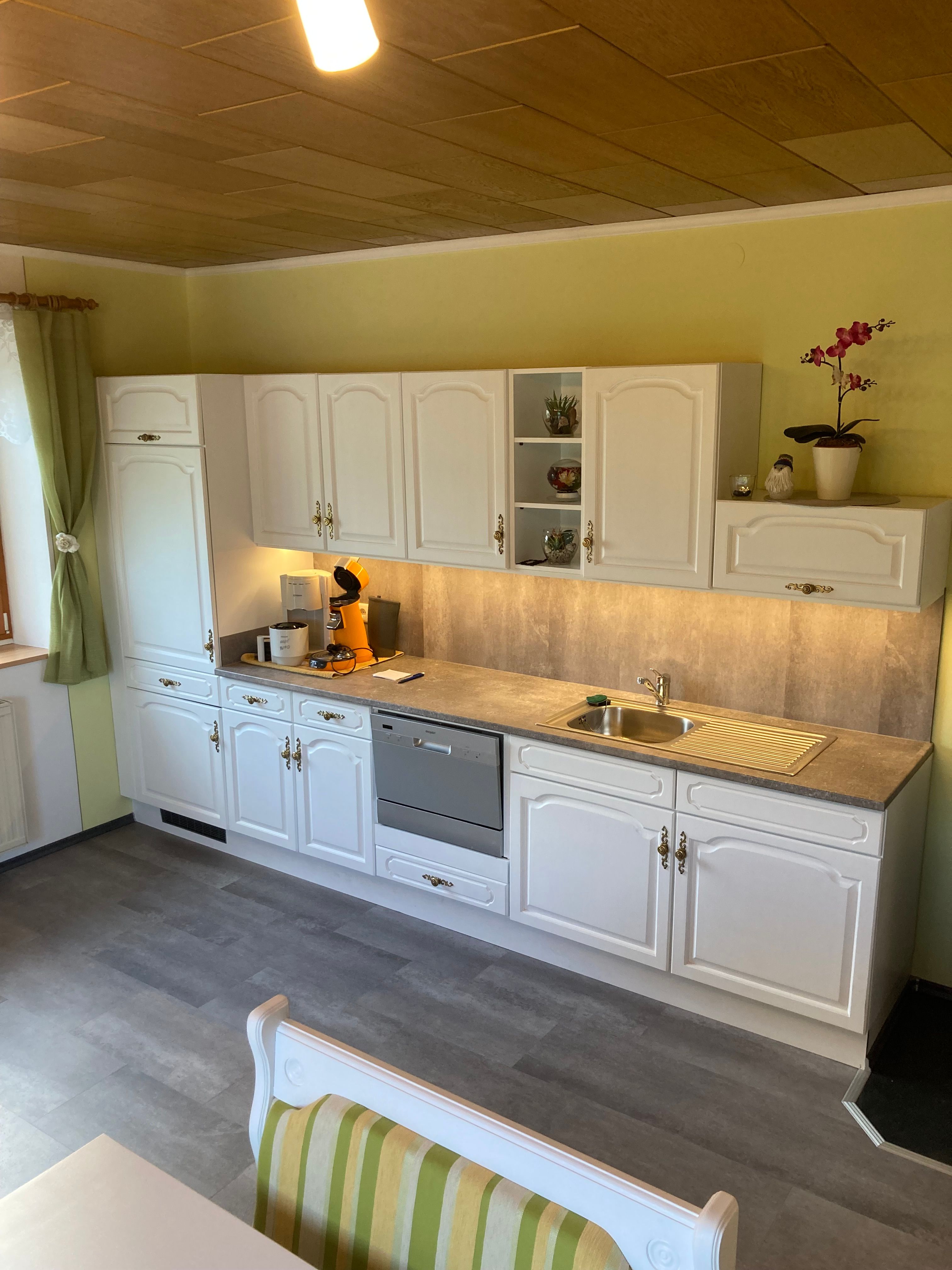 Küche mit weißen Schränken, Geschirrspüler und Spüle.