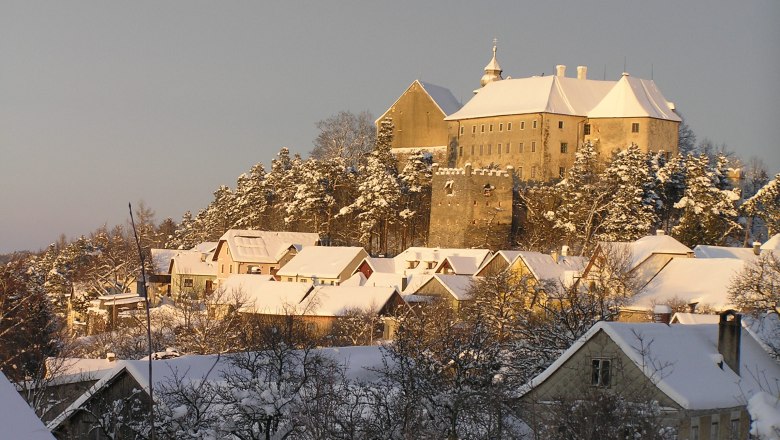 Winterliche Landschaft mit Schloss und schneebedeckten H&auml;usern.