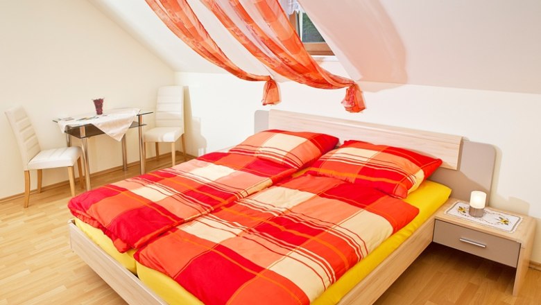 Bright bedroom with red comforter cover and decorative curtains.