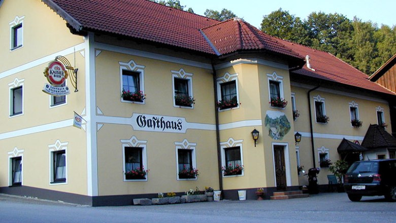 Ein traditionelles Gasthaus mit gelber Fassade und roten Dachziegeln.