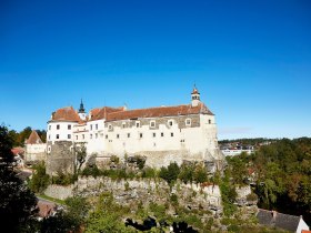 Die majest&auml;tische Burg Raabs thront stolz auf einem Felsen und bietet einen atemberaubenden Blick auf die umliegende Landschaft. Umgeben von &uuml;ppigem Gr&uuml;n und bl&uuml;henden B&auml;umen, strahlt sie eine Atmosph&auml;re von Geschichte und Abenteuer aus, die jeden Besucher in ihren Bann zieht.