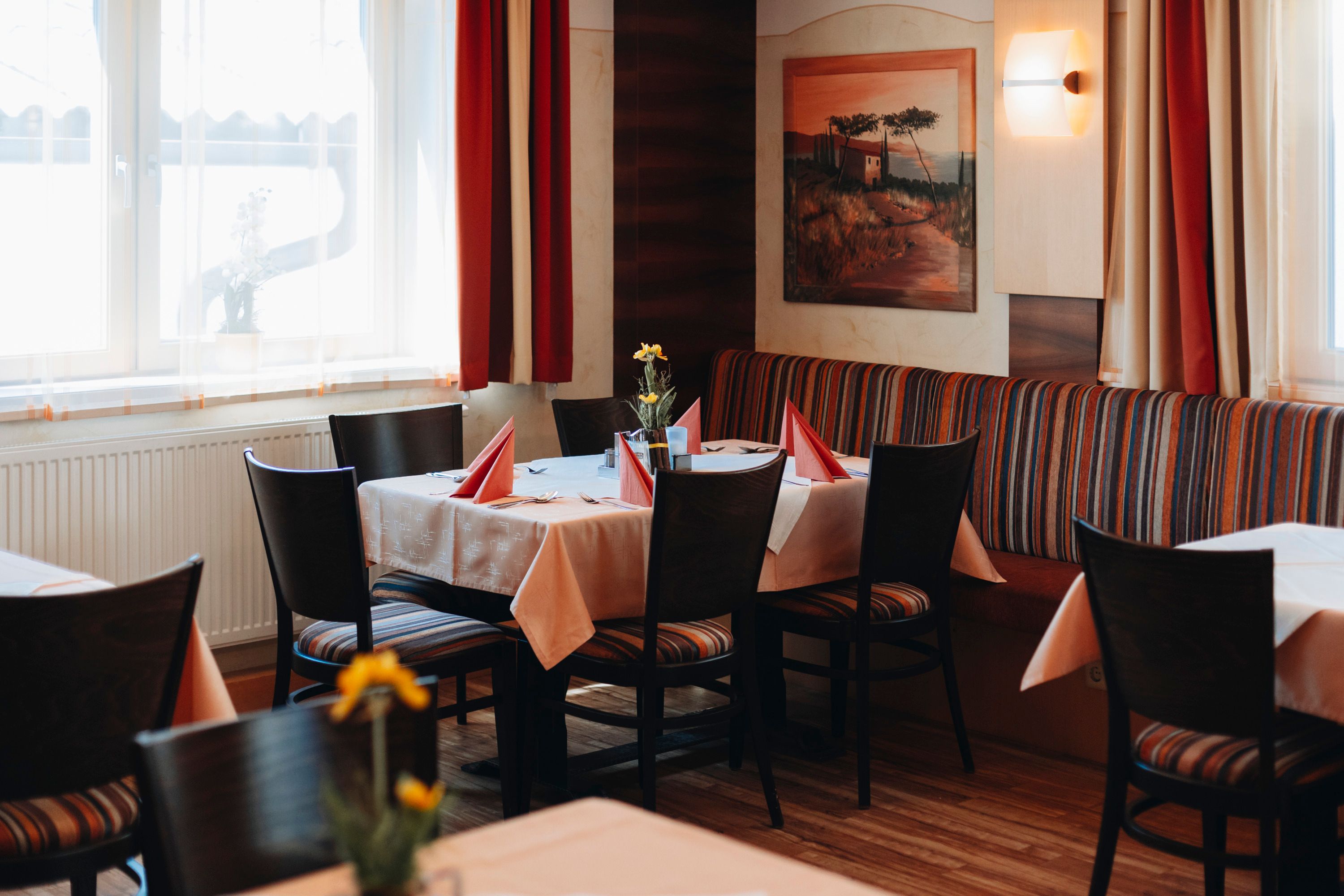 Gemütliches Restaurant mit gedecktem Tisch, roten Servietten und Blumen.