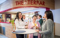 In der einladenden Atmosphäre der Theaterbar genießen Gäste erfrischende Getränke und anregende Gespräche. Die fröhlichen Gesichter und die stilvolle Einrichtung schaffen eine perfekte Kulisse für unvergessliche Momente. Hier trifft sich Kultur mit Geselligkeit und lädt zum Verweilen ein.