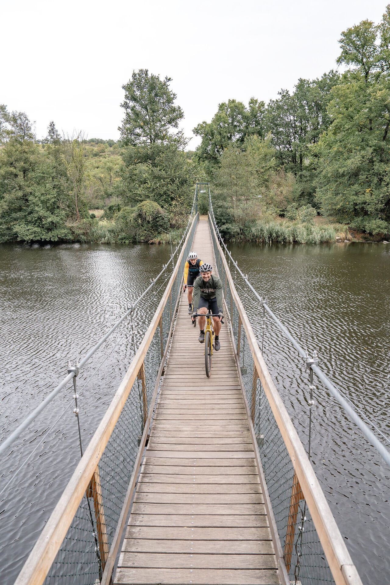 Die Hängebrücke schwingt sanft über das glitzernde Wasser, während Radfahrer die malerische Landschaft des Nationalparks Thayatal erkunden. Umgeben von üppigem Grün und dem sanften Plätschern des Flusses, bietet dieser Ort eine perfekte Kulisse für Abenteuer und Entspannung. Hier wird das Radfahren zum Genuss, während die Natur ihre Schönheit entfaltet.