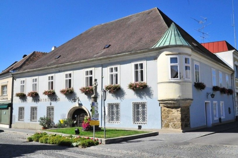 Historisches Gebäude mit blauer Fassade und Blumenkästen, Heimatmuseum Langenlois.