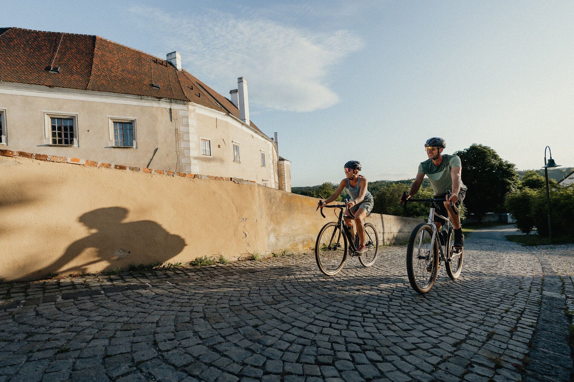 Ein Mann und eine Frau radeln bergauf entlang der Stadtmauer