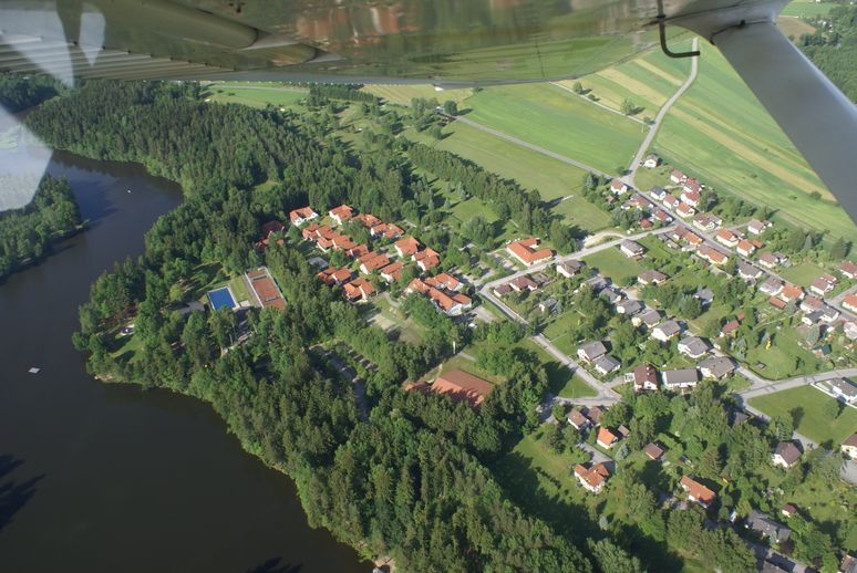 Luftaufnahme eines Golfplatzes und eines Sees mit angrenzender Wohnsiedlung.