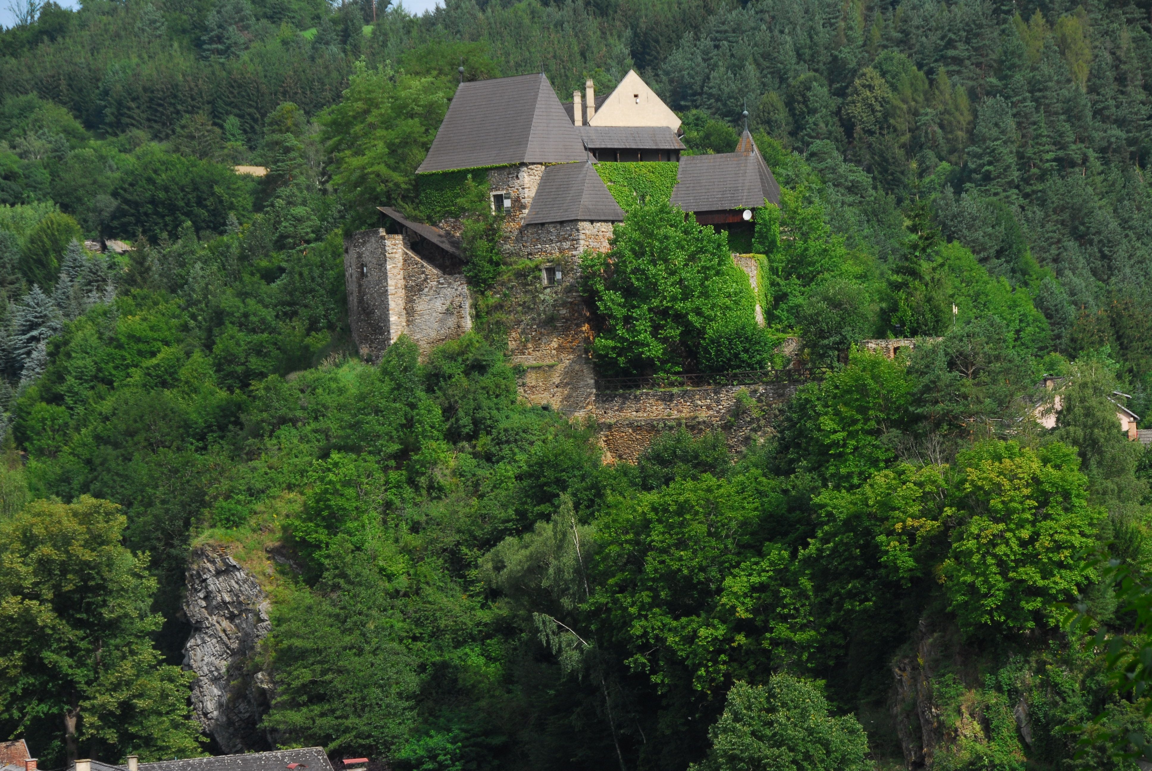 Burg inmitten von Bäumen auf einem Hügel.