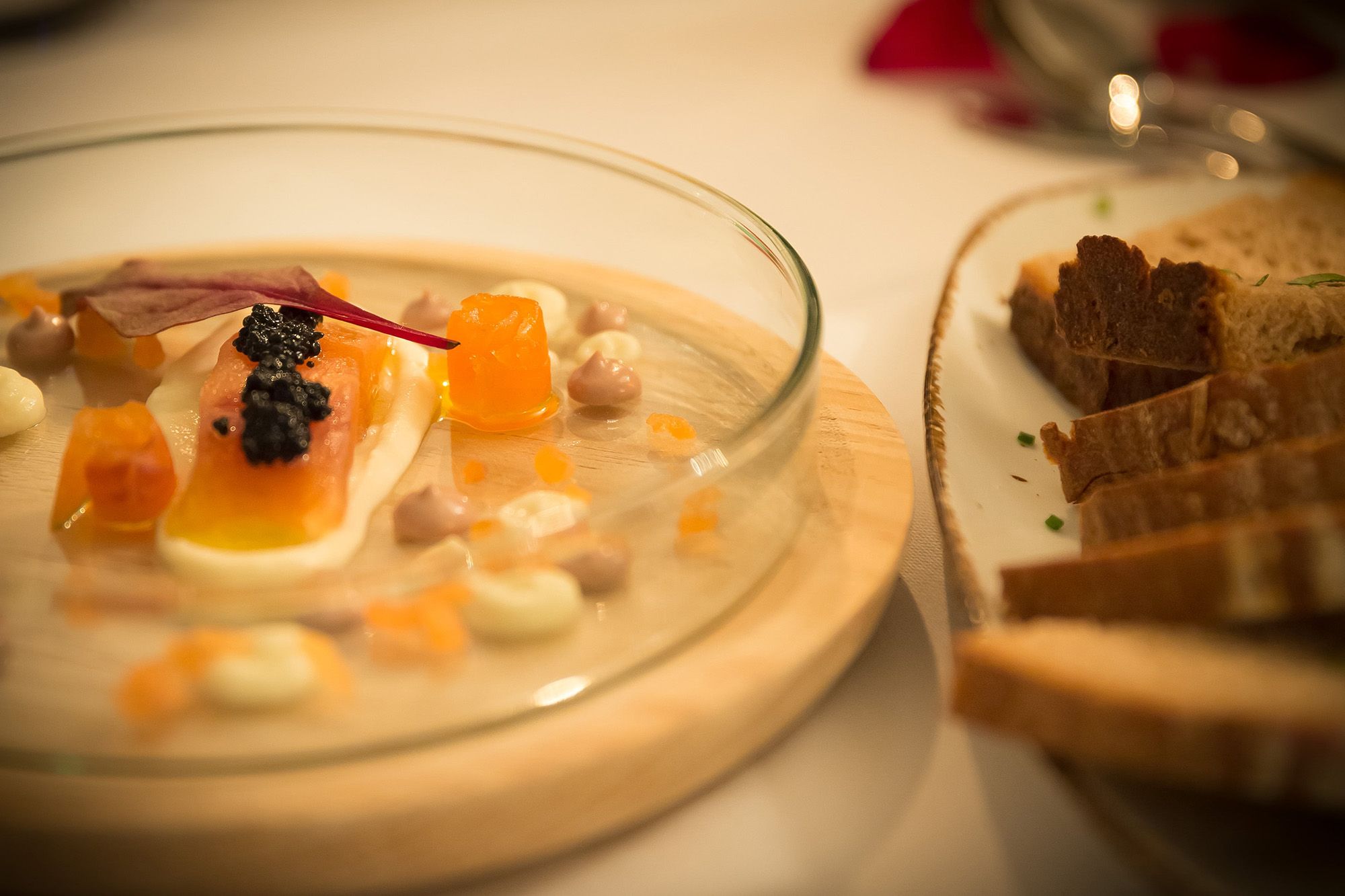 Hausgebeizte Lachsforelle mit Kaviar und Brot auf einem Teller.