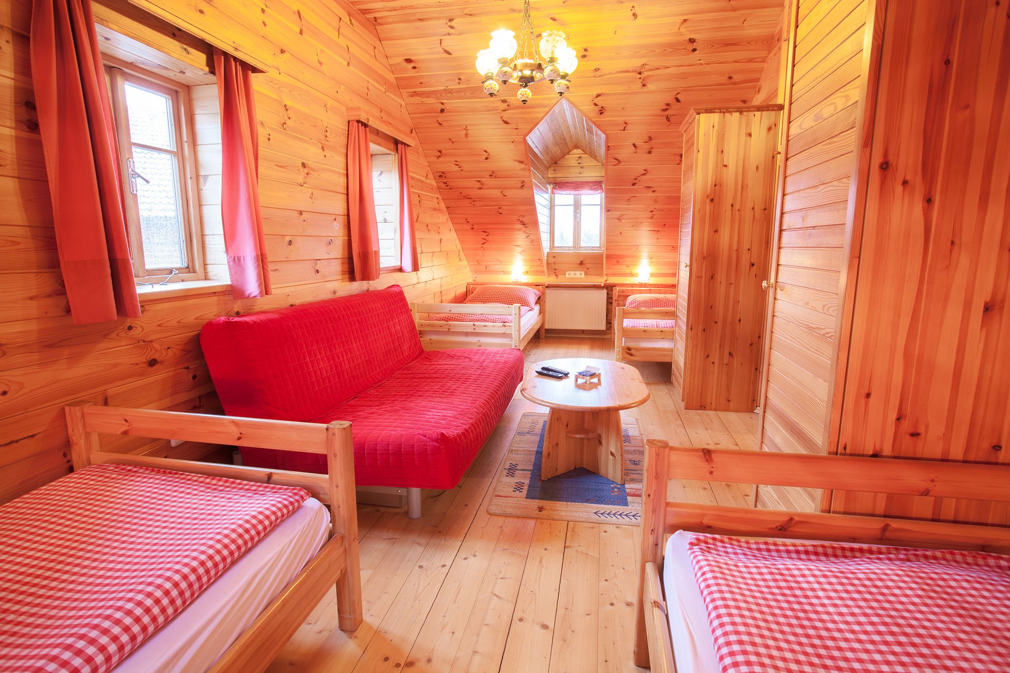 Holzvertäfeltes Zimmer mit roten Vorhängen und Möbeln.