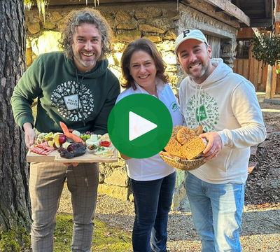 3 lachende Personen mit regionalen Lebensmittel mit Blick in die Kamera