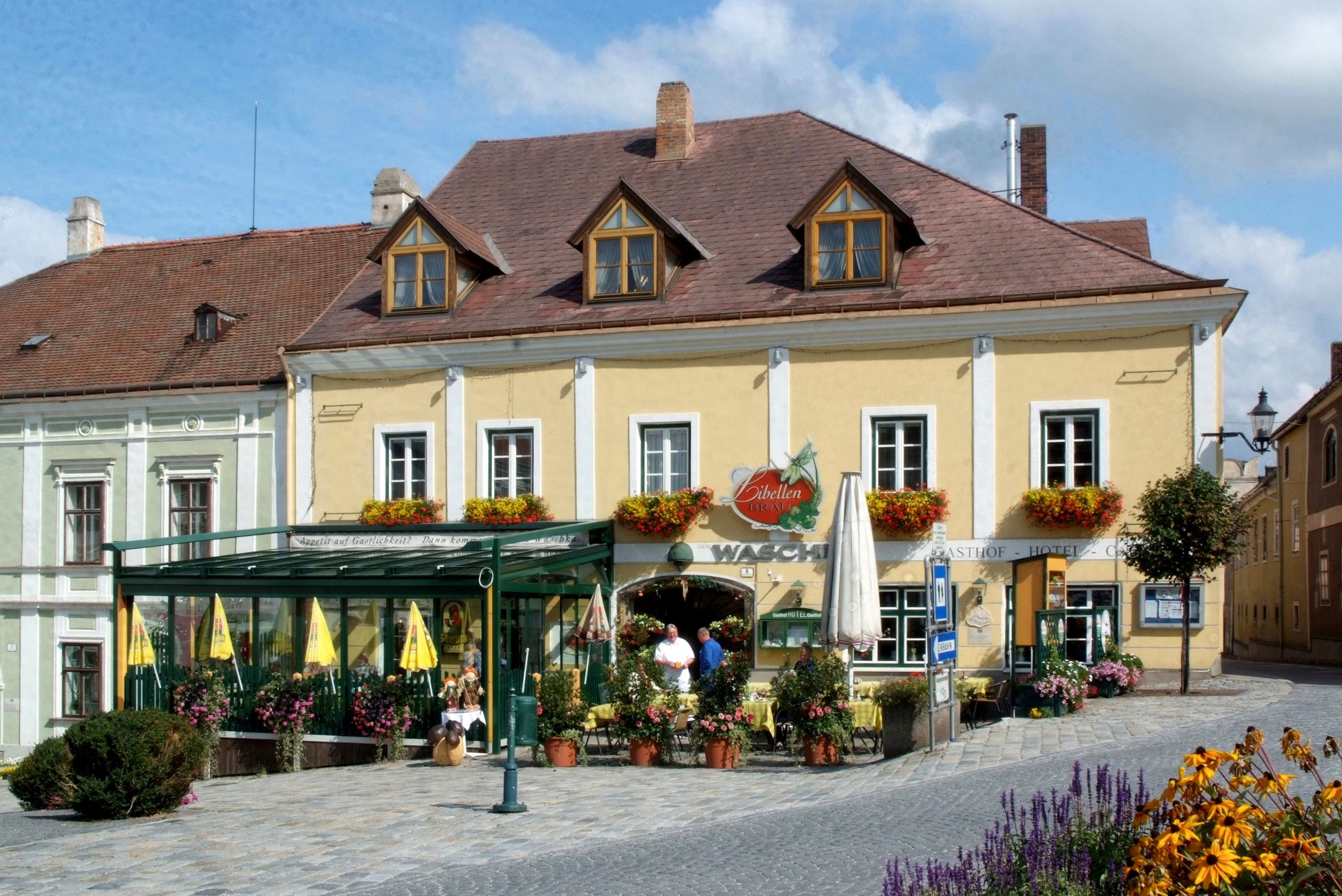 Ein traditionelles Gasthaus mit gelber Fassade und Blumendekorationen.