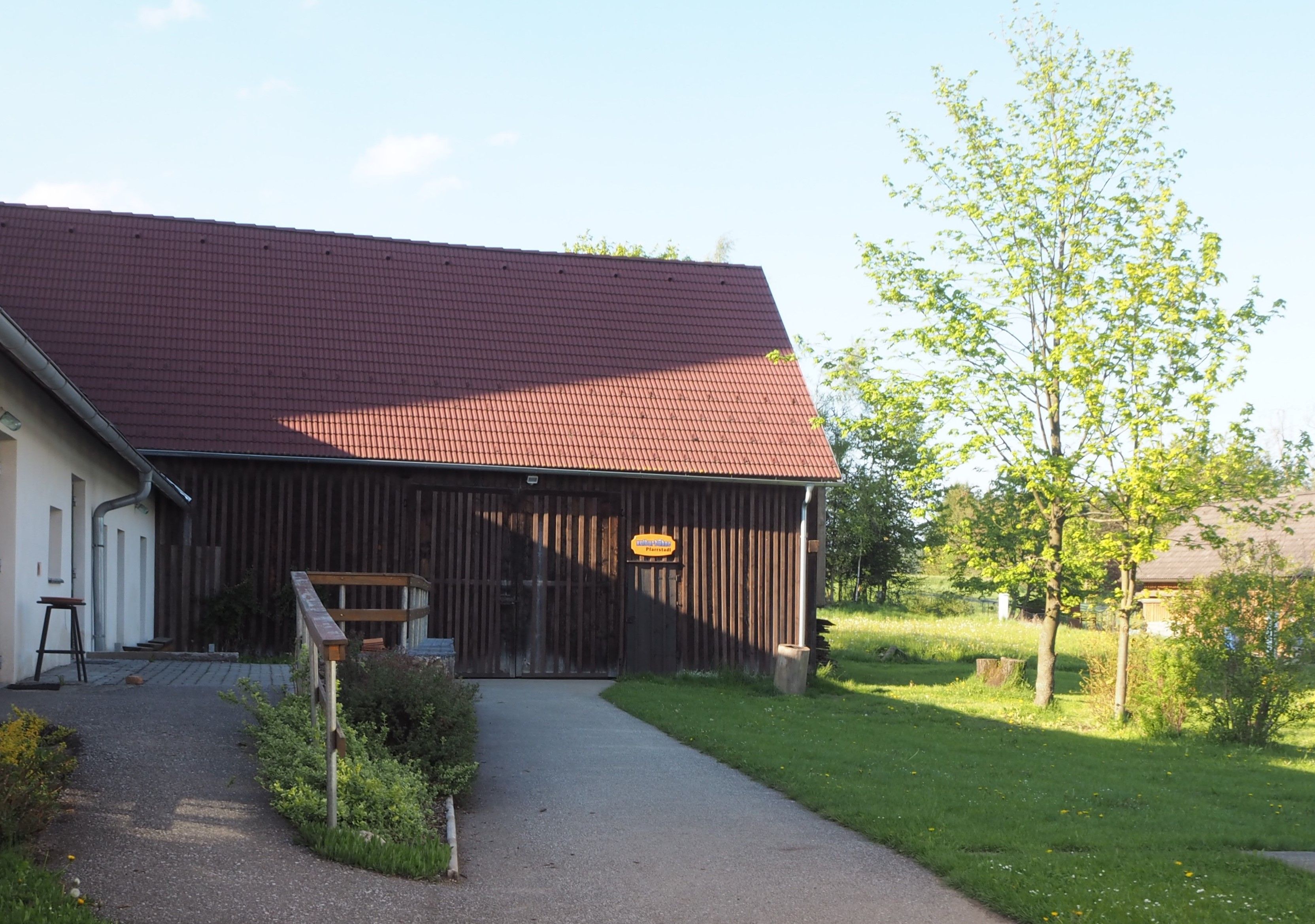 Ein Gebäude mit rotem Dach und Holzwänden, umgeben von grüner Landschaft und Bäumen.