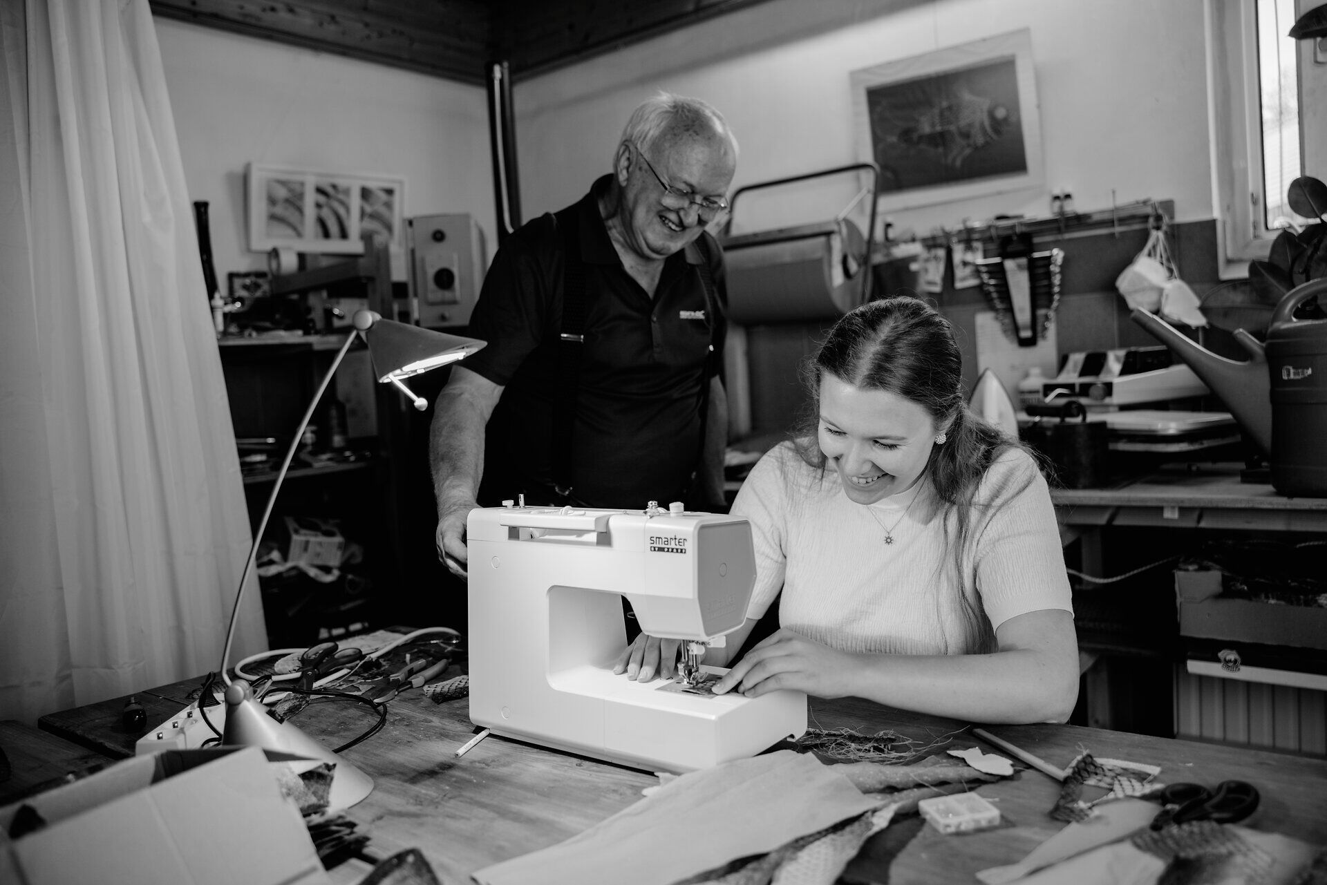 In einer gemütlichen Werkstatt arbeiten zwei Menschen mit Leidenschaft an einem kreativen Projekt. Die Atmosphäre ist von Freude und handwerklichem Können geprägt, während sie gemeinsam die Kunst des Fischleders entdecken. Hier wird Tradition lebendig und die Liebe zum Detail spürbar.