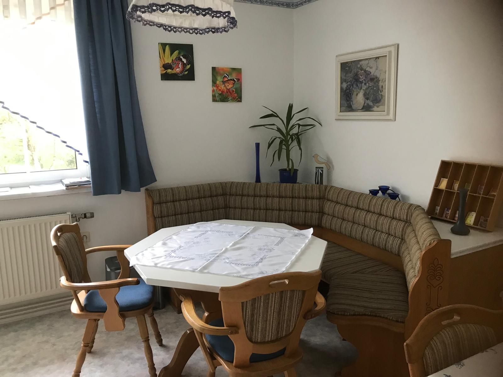 Eckbank in einer Küche mit Tisch und Stühlen, dekoriert mit Pflanzen und Bildern an der Wand.