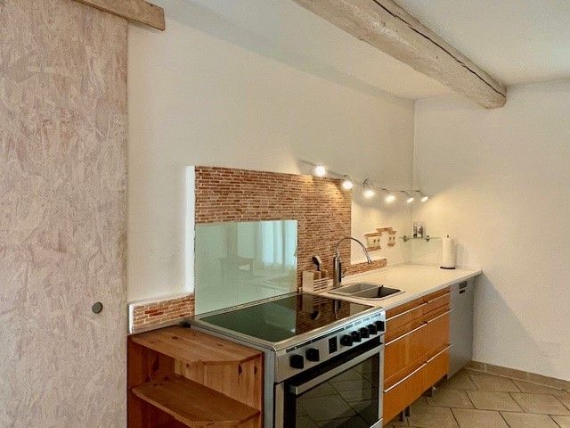 Moderne Küche mit Holzschränken, Herd, Spüle und Fliesenrückwand.