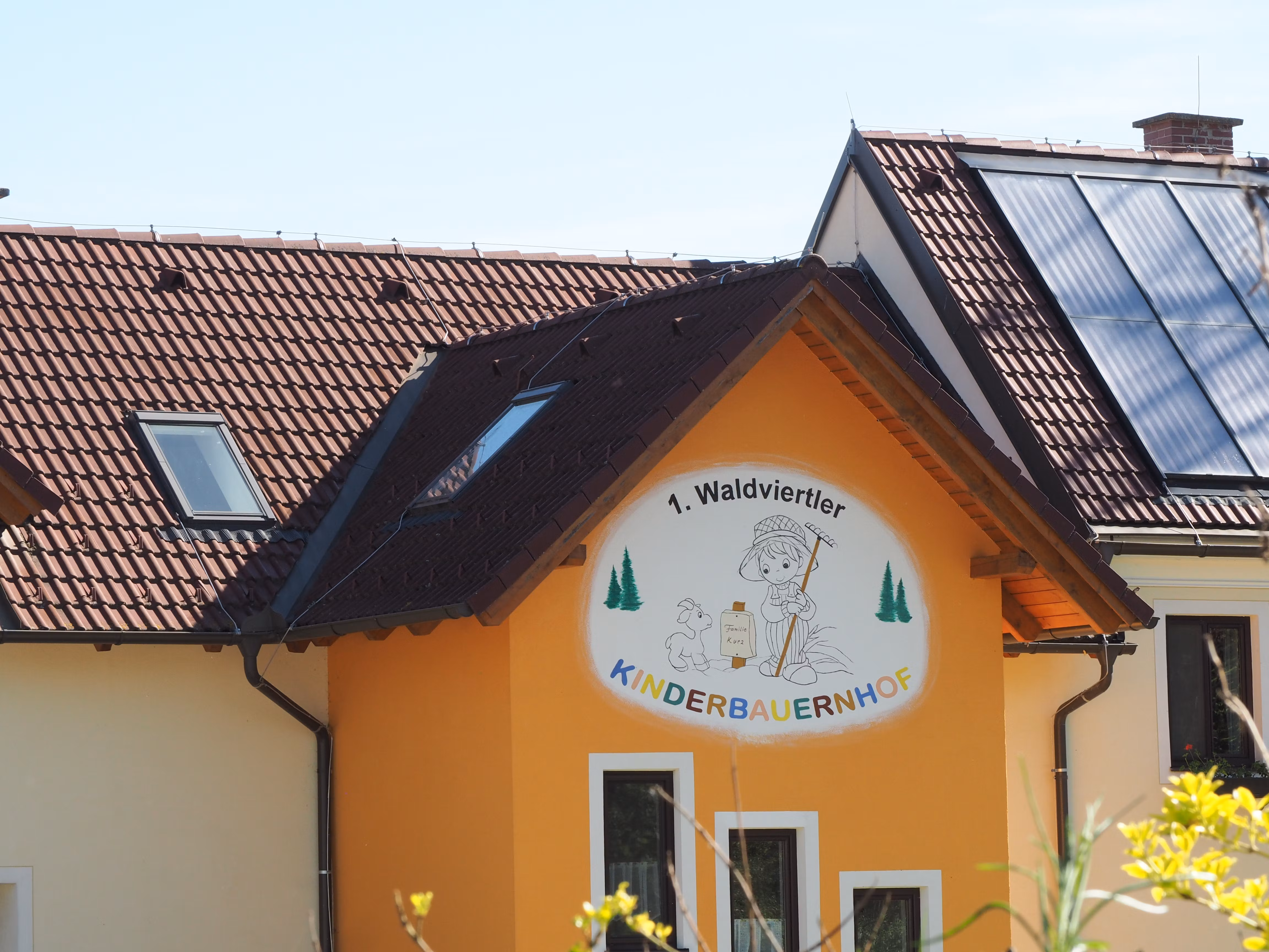 Gebäude mit Schild '1. Waldviertler Kinderbauernhof', Solarpanelen auf dem Dach.