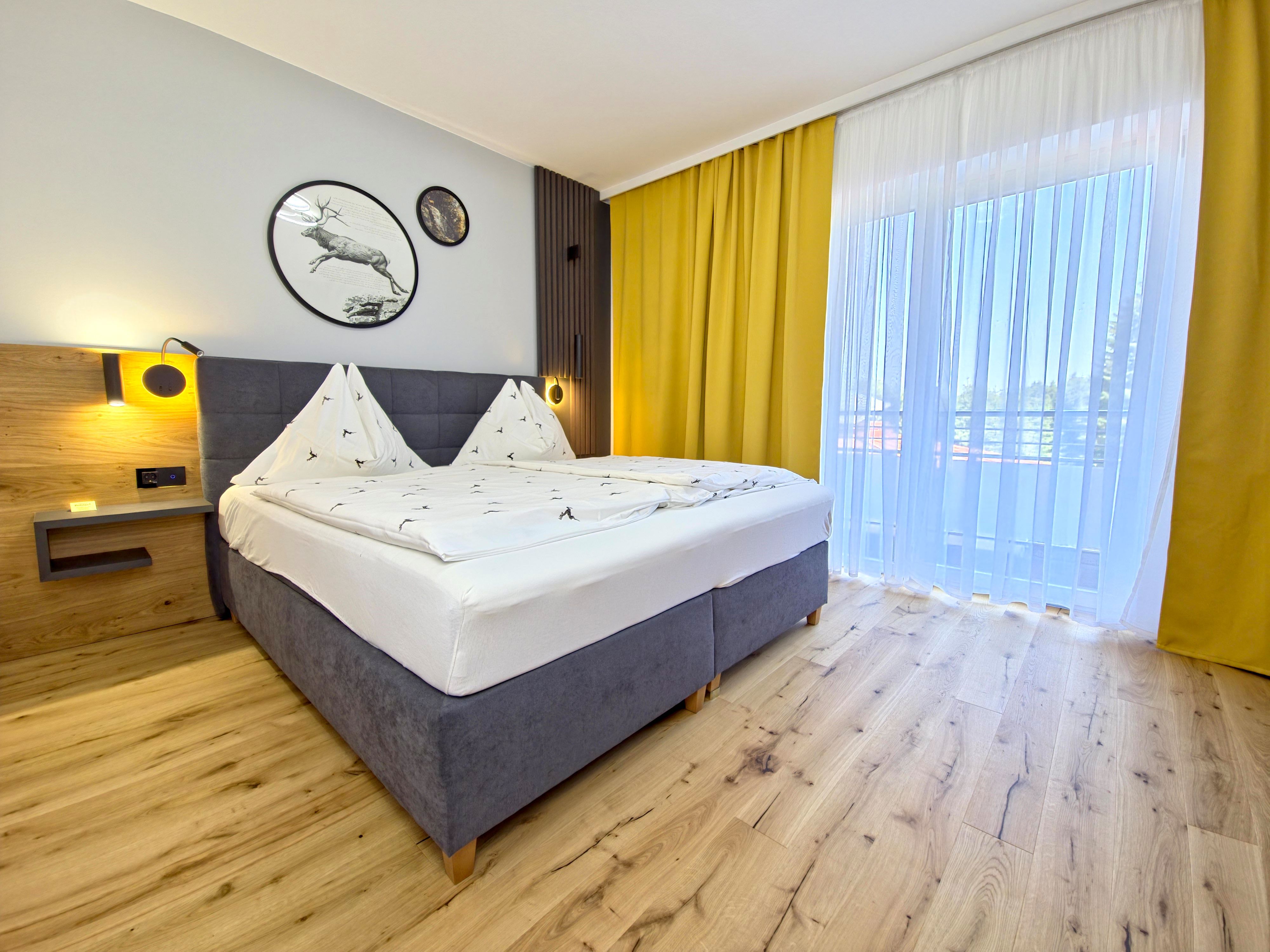 Modern eingerichtetes Schlafzimmer mit Doppelbett, Holzboden und gelben Vorhängen.