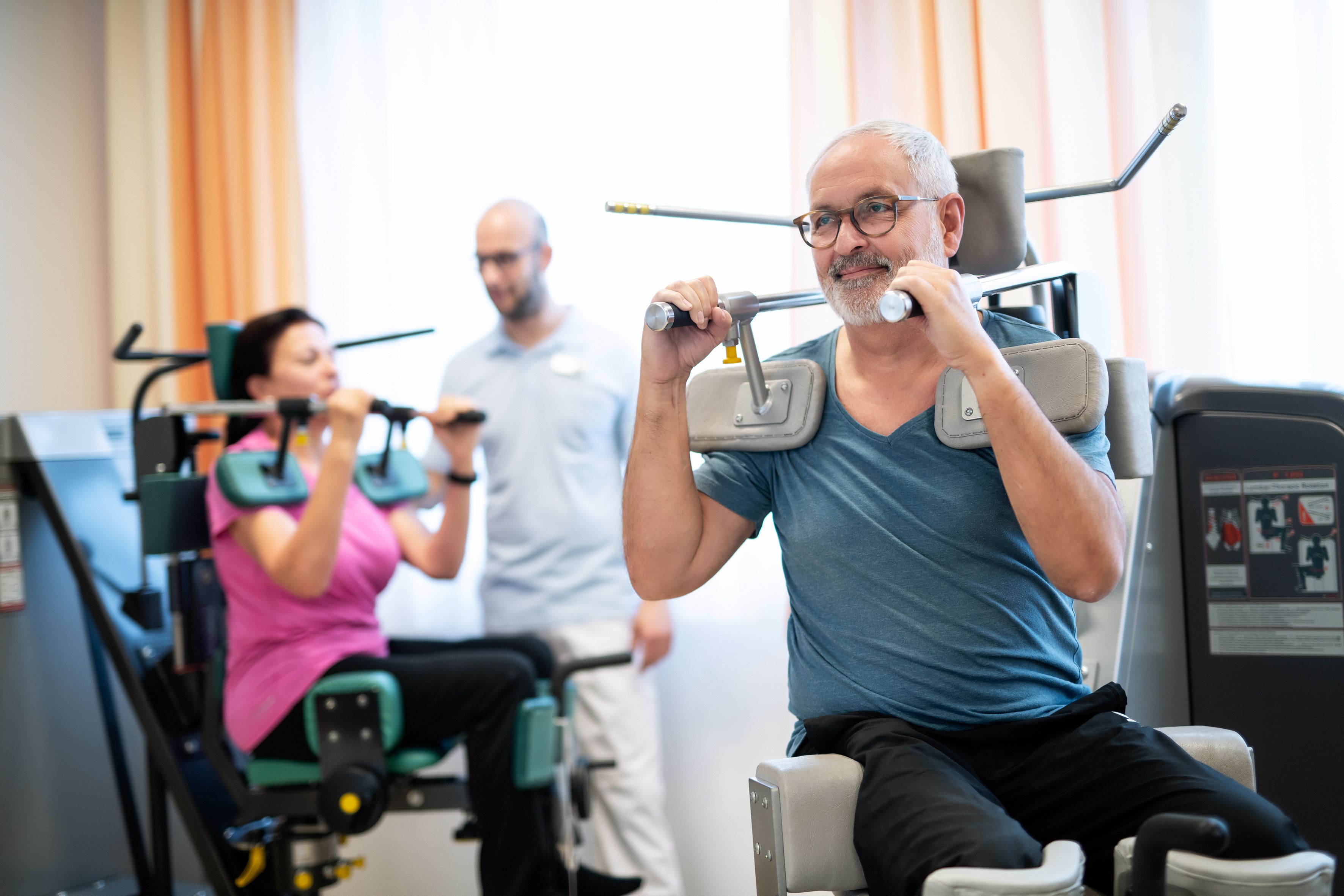 Personen trainieren an Fitnessgeräten in einem Rehabilitationszentrum.