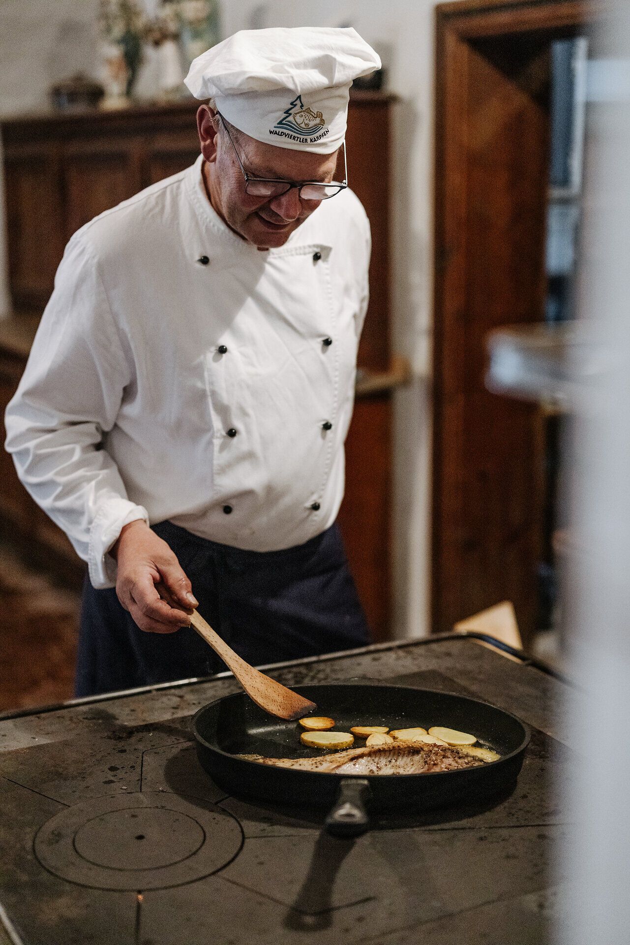 In einer gemütlichen Küche wird mit Hingabe ein traditionelles Gericht zubereitet. Der Duft von frisch gebratenem Karpfen erfüllt den Raum und weckt die Vorfreude auf ein köstliches Mahl. Hier erleben Besucher die Kunst des Kochens in einer einladenden Atmosphäre.