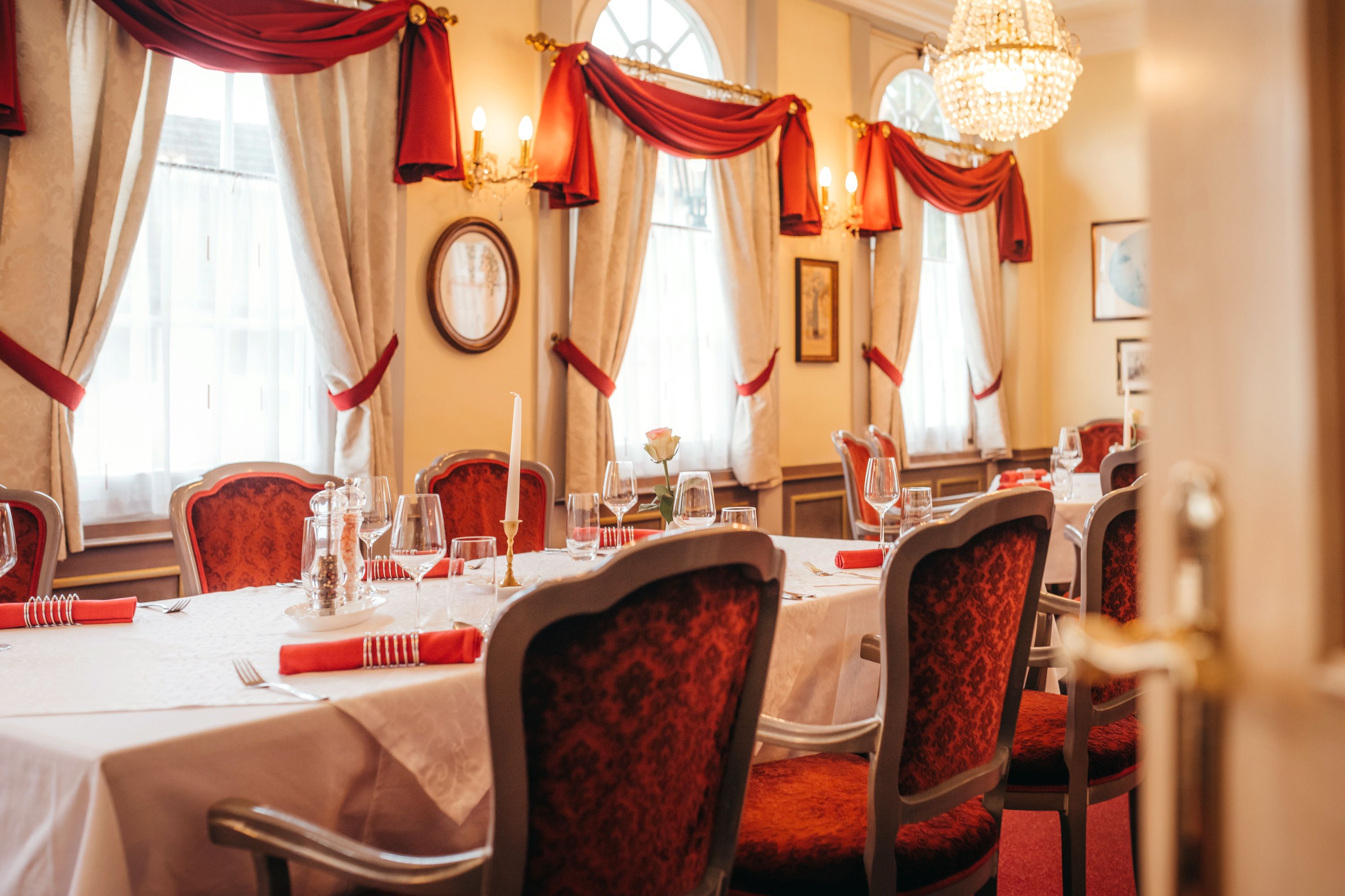 Elegantes Restaurant mit gedecktem Tisch, roten Stühlen und Kronleuchter.