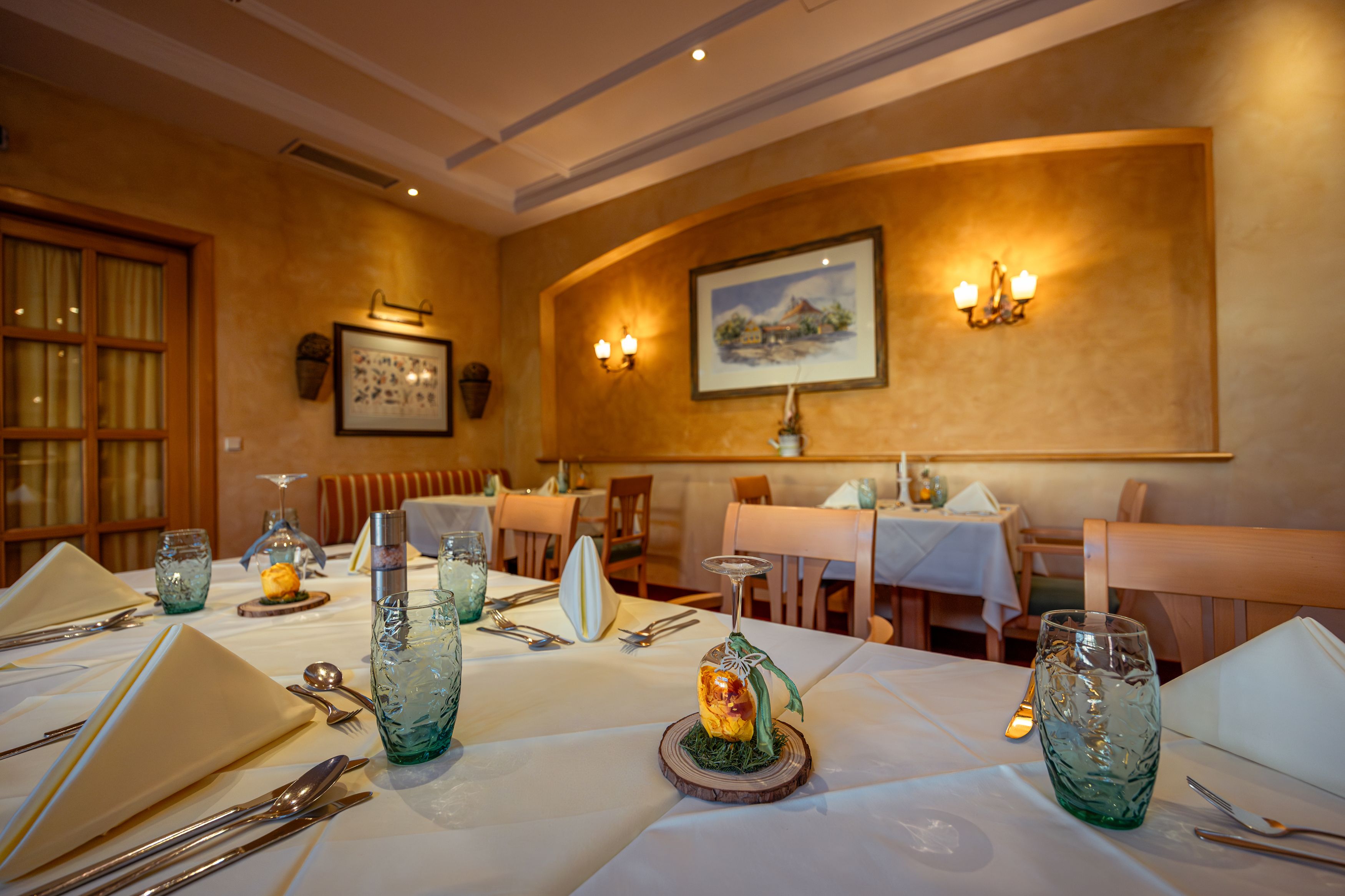 Elegantes Restaurant mit gedeckten Tischen, weißen Tischdecken und dekorativen Gläsern.