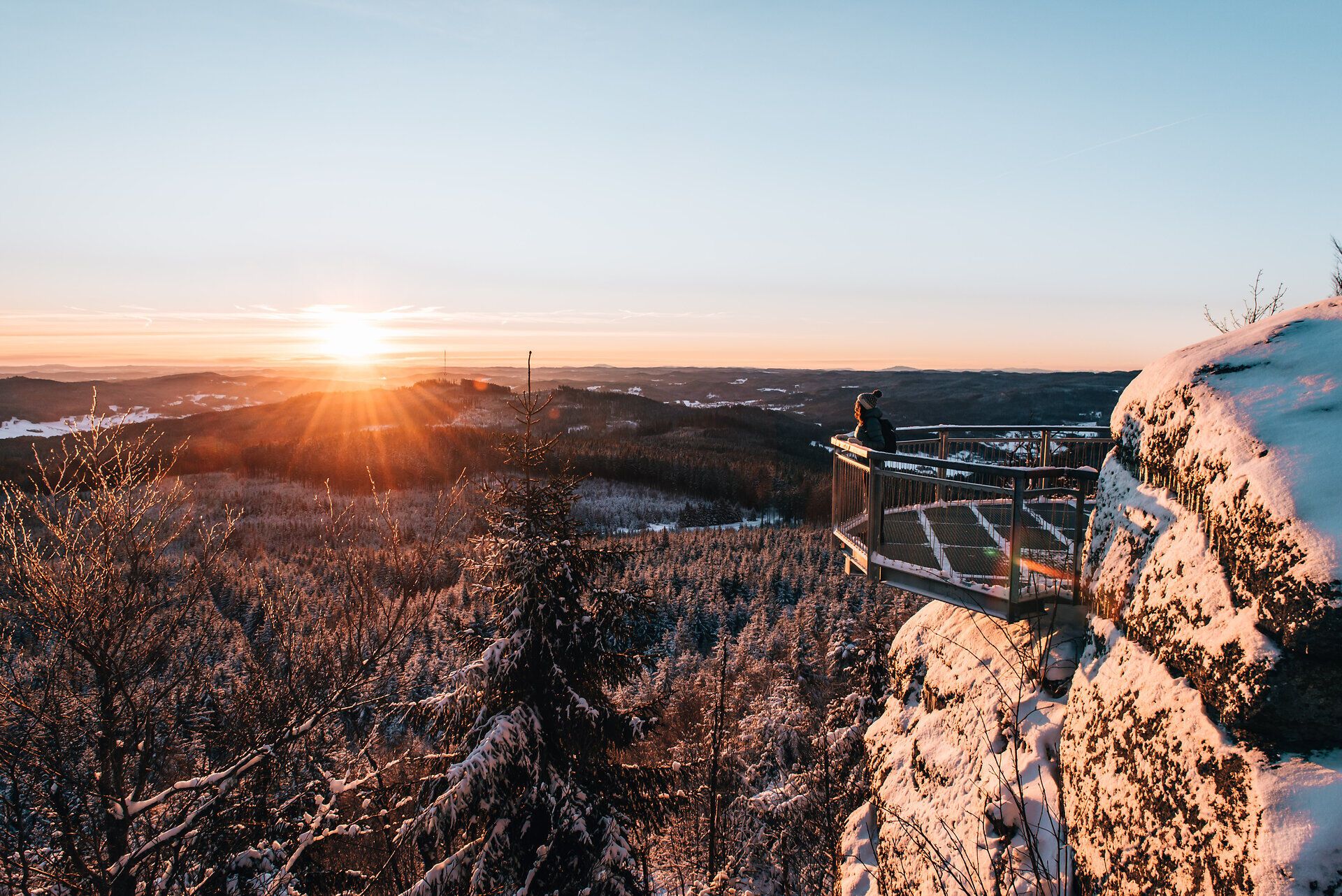 Die Wintersonne taucht die verschneite Landschaft in ein warmes Licht, während die schneebedeckten Bäume sanft im Wind wiegen. Ein atemberaubender Ausblick lädt dazu ein, die Ruhe der Natur zu genießen und die frische, klare Luft einzuatmen.