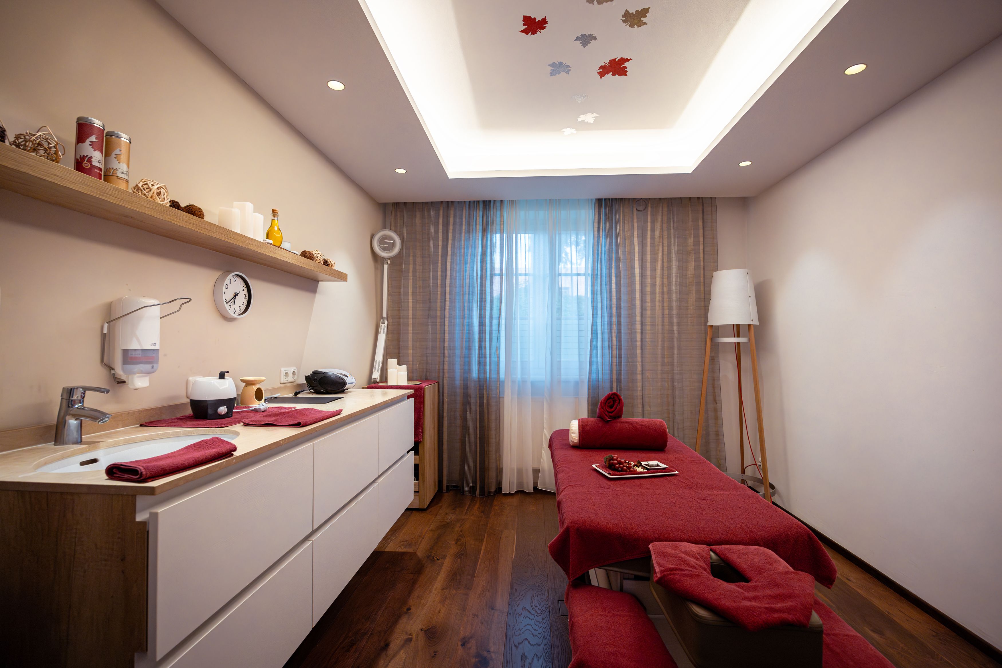 Ein stilvoll eingerichteter Spa-Raum mit Massageliege, roten Handtüchern und dekorativen Elementen.