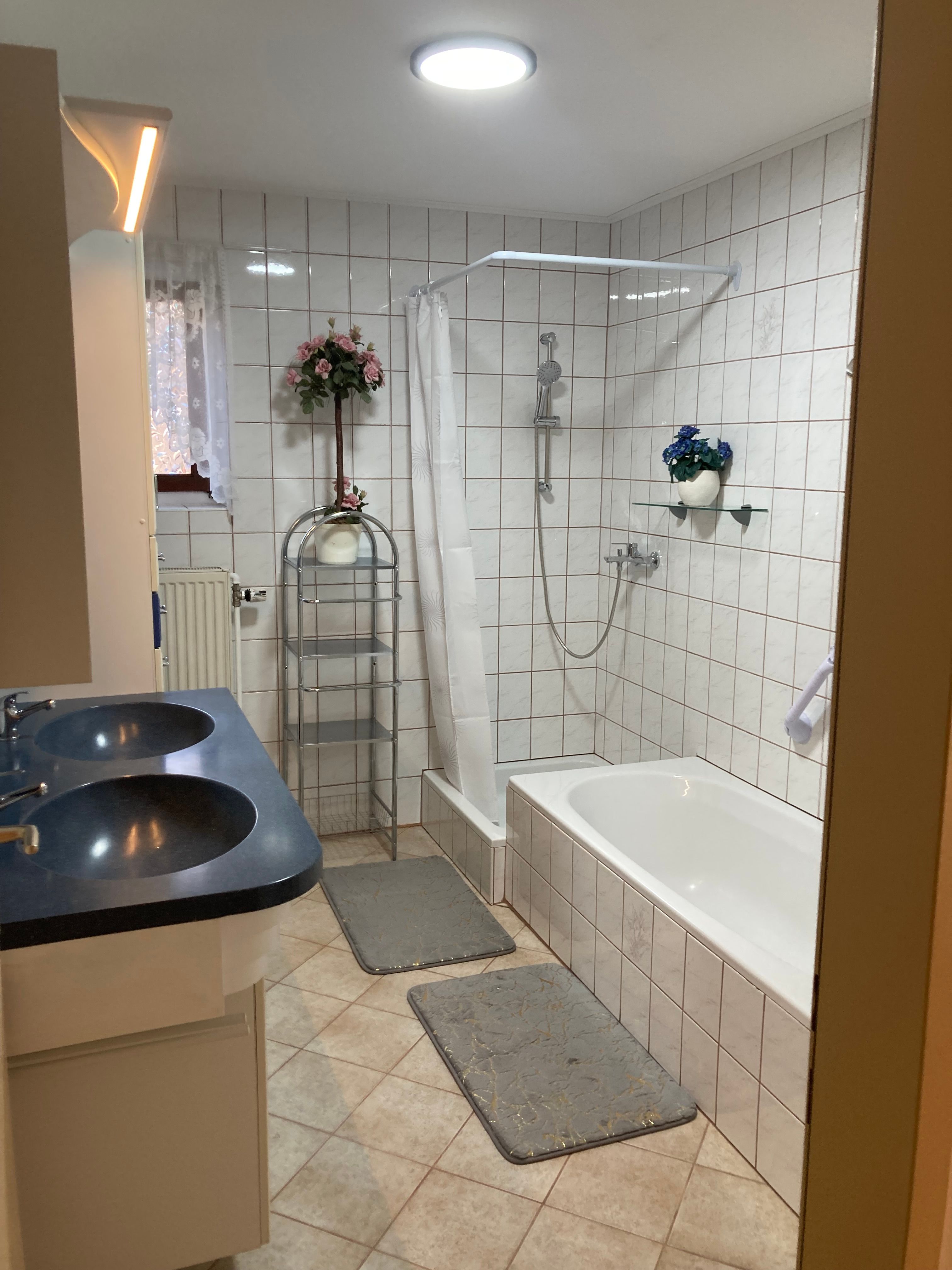 Badezimmer mit Badewanne, Doppelwaschbecken und Dusche mit Duschvorhang.