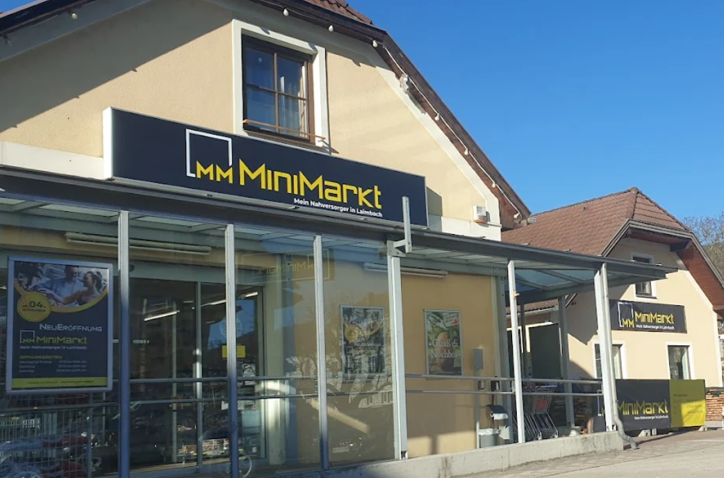 Außenansicht eines MiniMarkt-Geschäfts mit Glasfassade und Werbeplakaten.