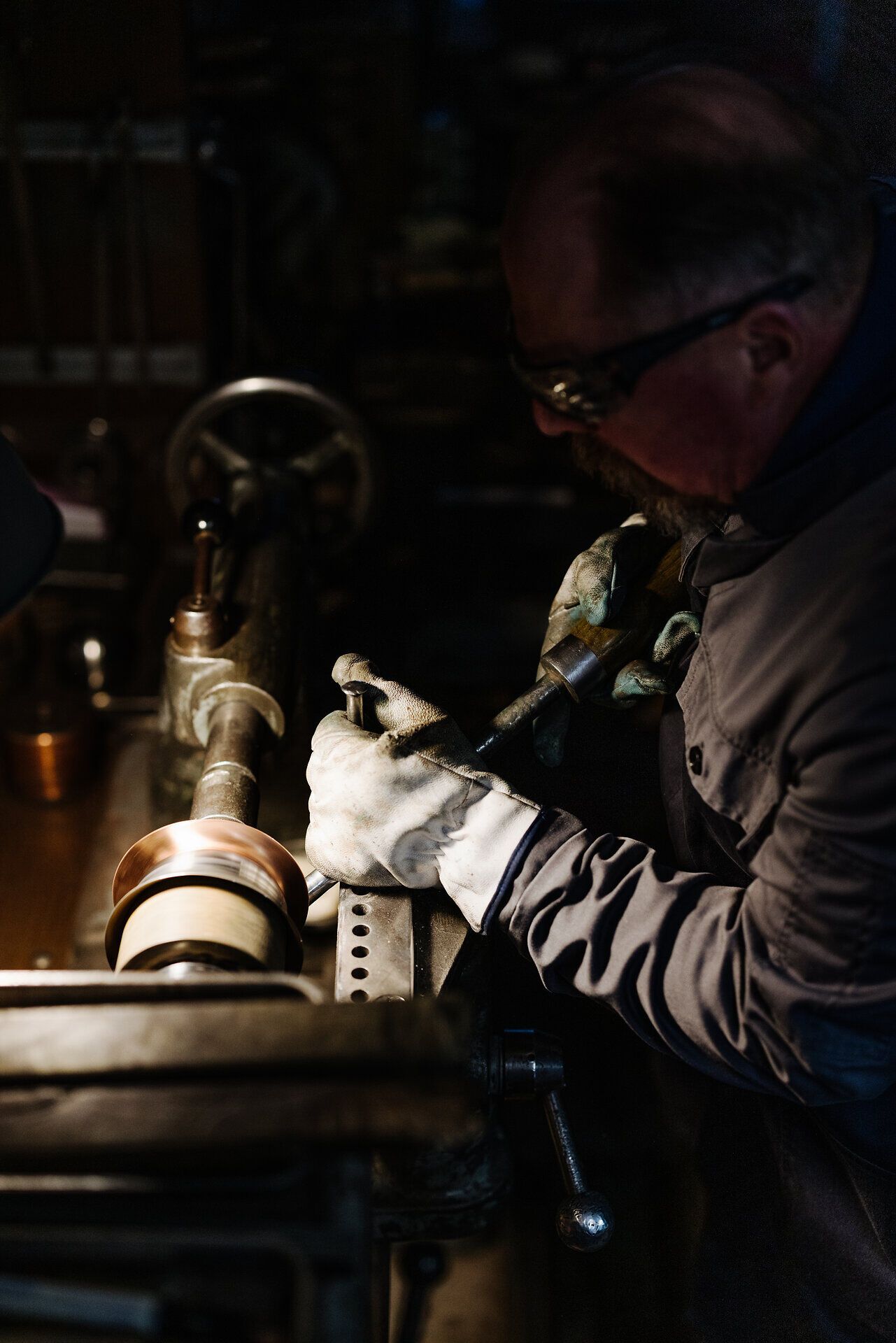 In einer Werkstatt, umgeben von funkelndem Metall und dem Geruch von frischem Kaffee, arbeitet ein Handwerker konzentriert an einer Kaffeekanne. Die sanften Bewegungen seiner Hände zeugen von jahrelanger Erfahrung und Leidenschaft für das Handwerk. Hier wird Tradition lebendig, während die Maschinen leise surren und die Atmosphäre von Kreativität und Hingabe erfüllt ist.
