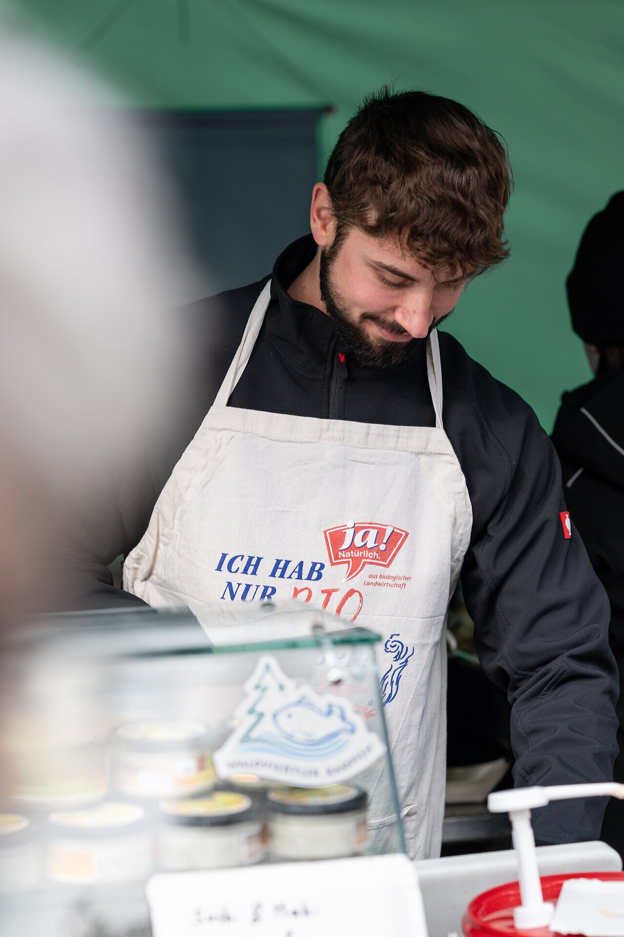Ein junger Mann in einem traditionellen Schürzenoutfit bereitet mit Hingabe frische Karpfen für die Besucher vor. Die Atmosphäre ist lebhaft und einladend, während die Gäste die Köstlichkeiten des Abfischfests genießen. Umgeben von der malerischen Natur des Waldviertels wird hier ein unvergessliches Erlebnis geboten.