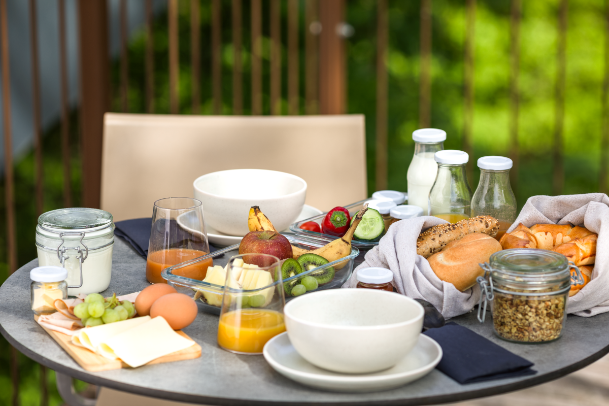 Frühstückstisch mit Obst, Brot, Joghurt und Saft.