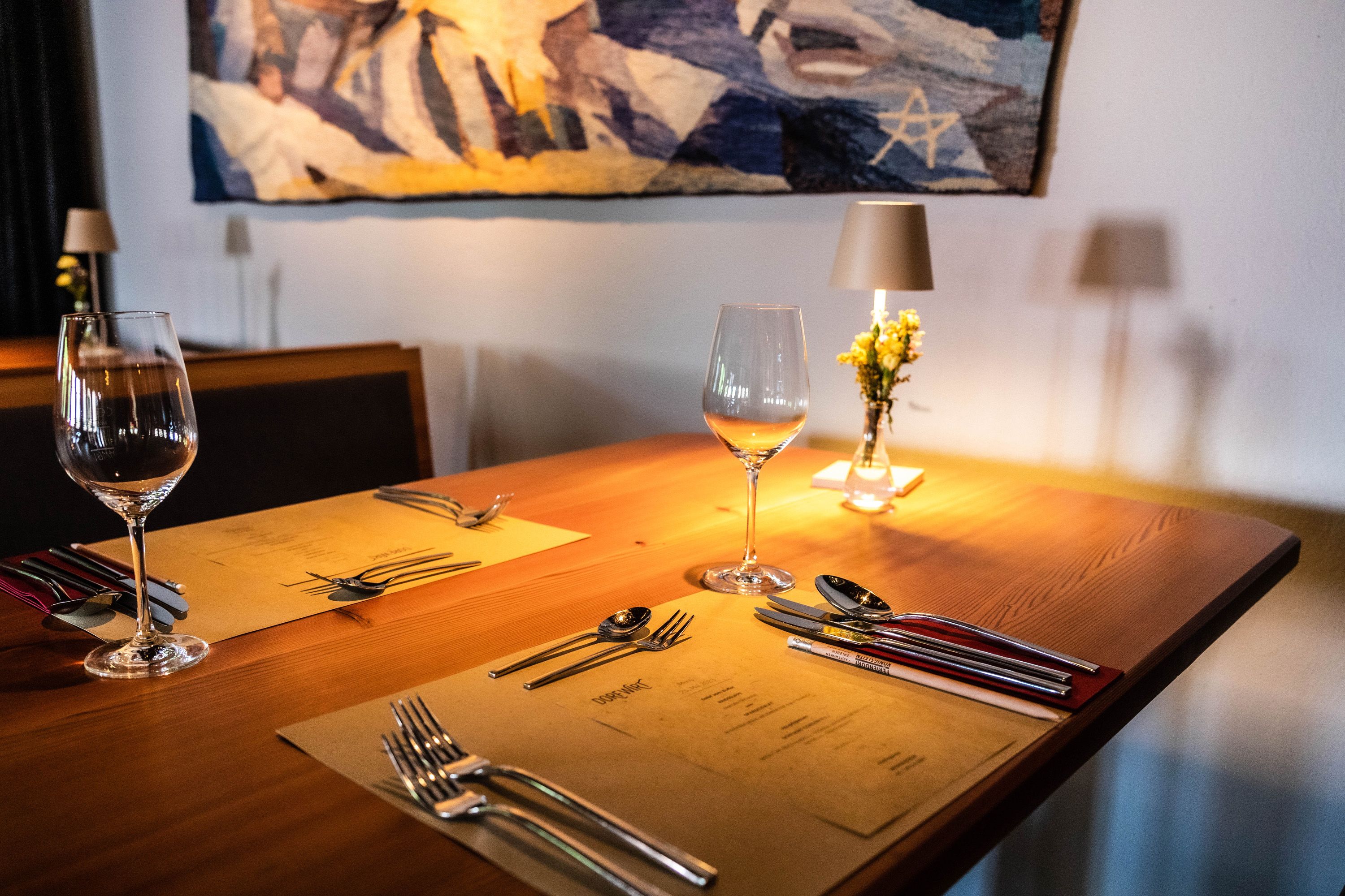 Eleganter Tisch in einem Restaurant mit Weingläsern, Besteck und Blumen.