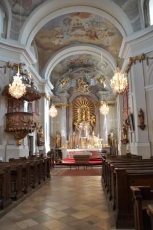 Innenansicht einer barocken Kirche mit Altar, Kanzel und Kronleuchtern.