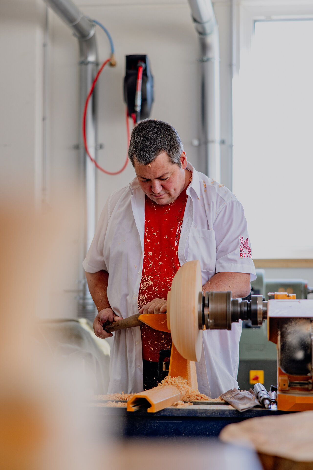 In der gemütlichen Werkstatt der Drechslerei Reiter wird mit viel Geschick und Leidenschaft an einem Holzstück gearbeitet. Der feine Duft von frischem Holz und das sanfte Geräusch der Drechselmaschine schaffen eine einladende Atmosphäre, die die Kunst des Handwerks lebendig werden lässt.