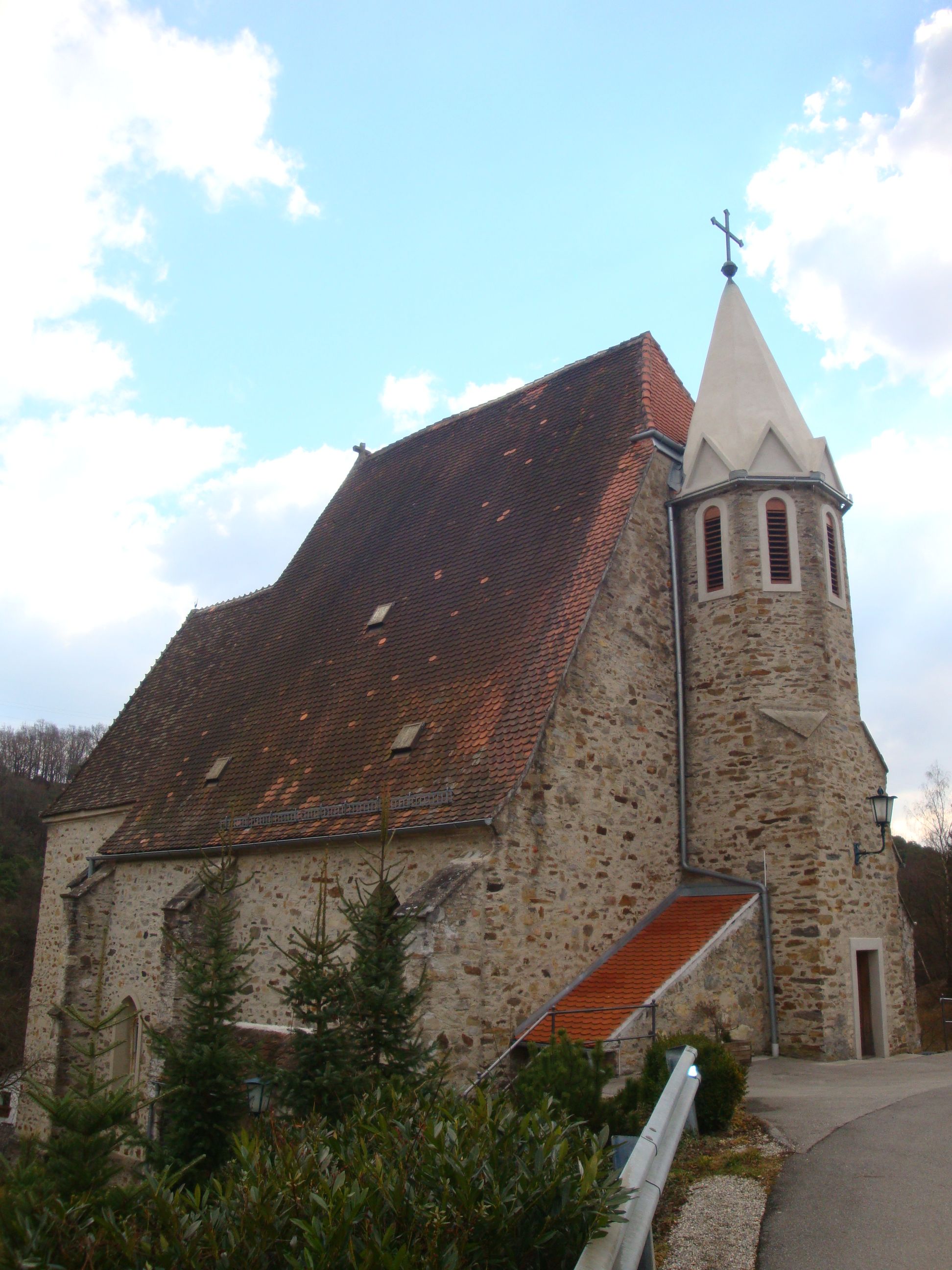Pfarrkirche Pöbring mit steilem Dach und Turm vor blauem Himmel.