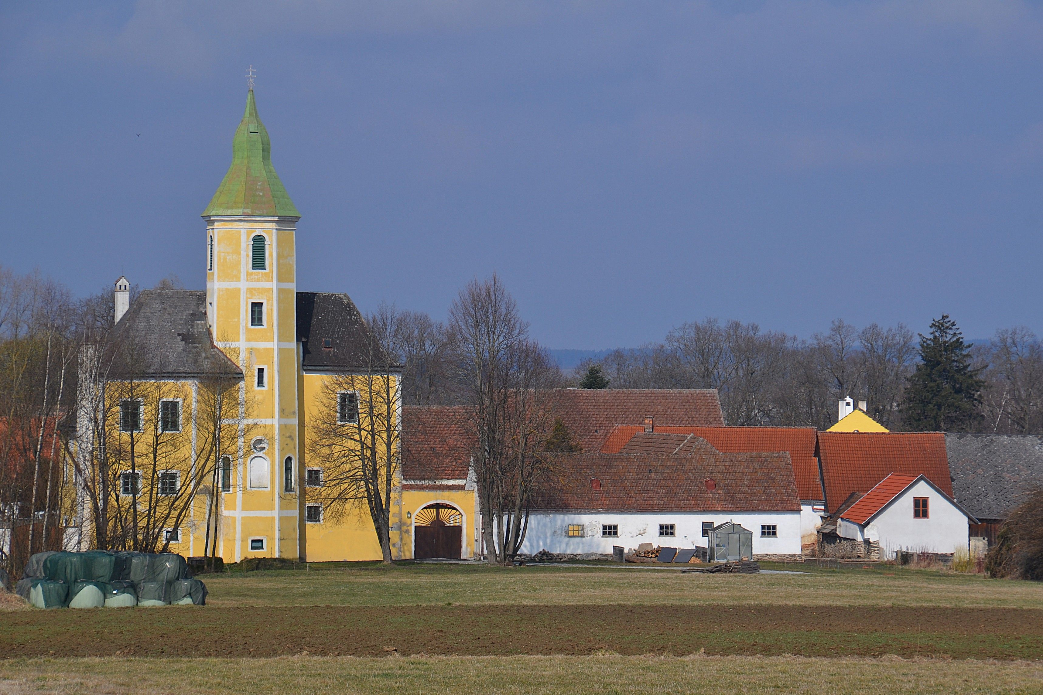 Gelbes Gebäude mit Turm neben weiteren kleineren Gebäuden