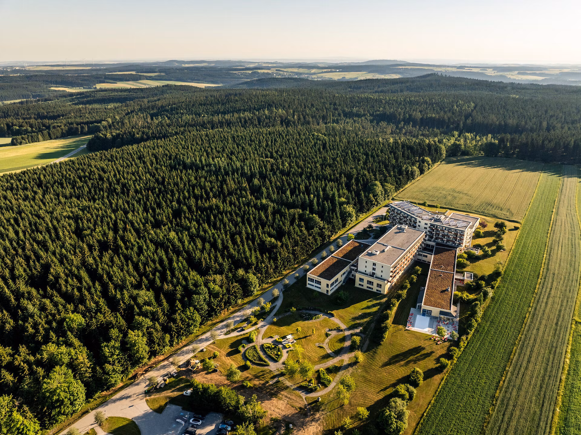 Luftaufnahme des Lebens.Resorts Ottenschlag im Waldviertel, umgeben von Feldern und dichtem Wald.