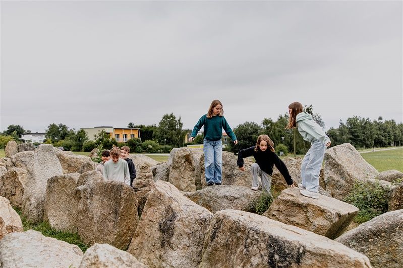 Kinder spielen auf großen Felsen in einer natürlichen Umgebung.