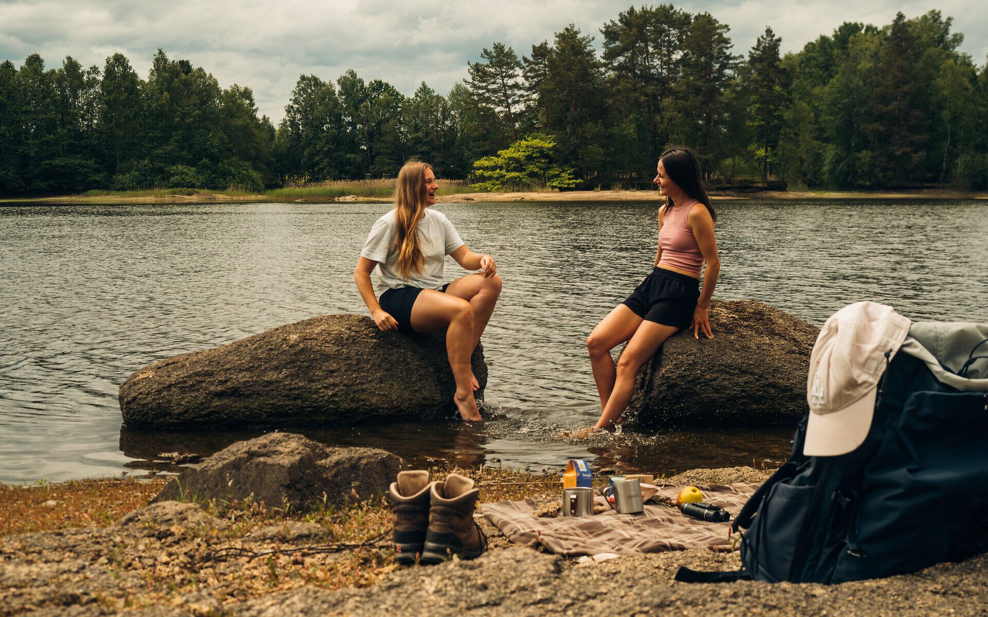 Zwei Frauen, die auf Steinen, im Teich sitzen und sich unterhalten