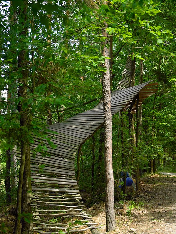 Holzkunstwerk in einem Wald, das sich zwischen Bäumen erstreckt.